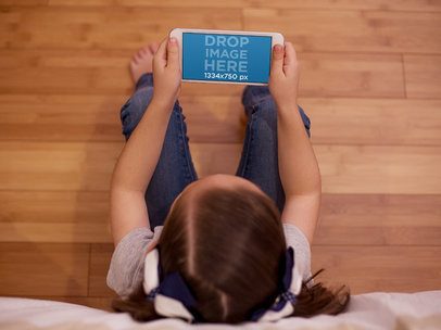 Young Girl Sitting in her Room and Using an iPhone 7 in Landscape Position Mockup