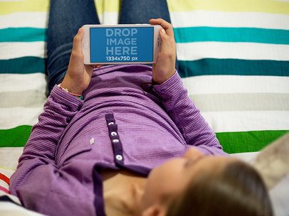 iPhone 7 Mockup Featuring a Little Girl Playing with her iPhone in Bed