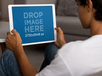 Mockup of an iPad Pro Held in Landscape Position by a Young Man Playing in his Living Room a13036