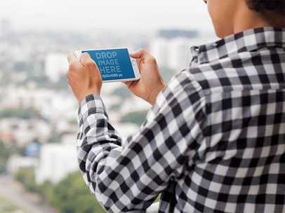 Mockup of an iPhone in Landscape Position Featuring a Man in an Urban Background