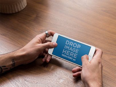 Mockup Featuring a Man Holding an iPhone in Landscape Position 