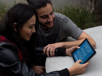 Mockup of a Young Couple Using an iPad in Landscape Position at their Terrace