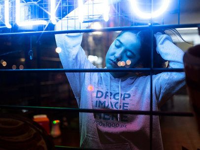 Pretty Asian Woman with Long Hair Wearing a Hoodie Mockup at a Cafe with Neon Lights a12714