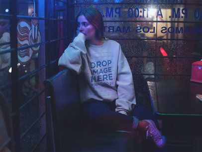 Young Woman with a Crewneck Sweatshirt Mockup Staring Out the Window