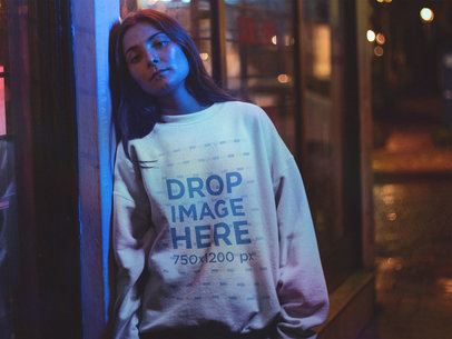 Young Woman Wearing a Crewneck Standing Under a Blue Light at Night