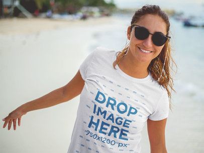 Smiling Lovely Woman Wearing a T-Shirt Mockup and Sunglasses at the Beach a12725