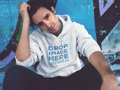 Pullover Hoodie Mockup of a Handsome Man Sitting at a Skate Park