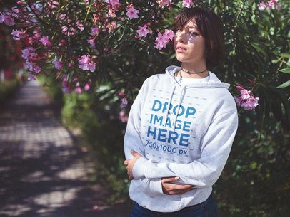 Lovely Woman with Short Hair Wearing a Hoodie Mockup Near a Garden Alley