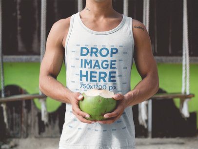 Tank Top Mockup of a Guy at the Beach Drinking a Coconut