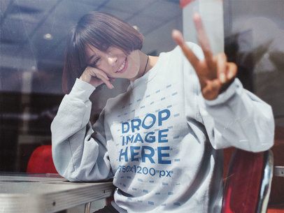 Crewneck Mockup of a Smiling Young Asian Woman Doing a Peace Sign Pose