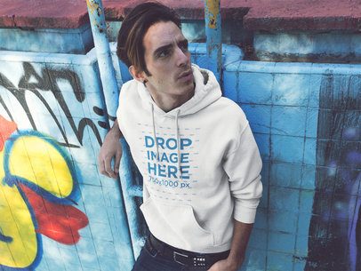 Pullover Hoodie Mockup Featuring a Trendy Guy Against a Graffiti Wall in the Street