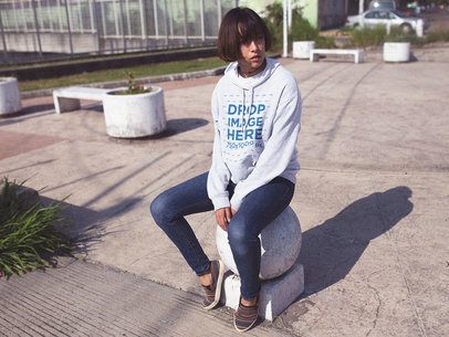 Pullover Hoodie Mockup Featuring a Woman with Short Hair Sitting in a Park