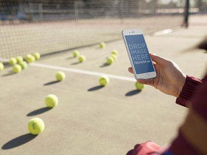 Mockup of a Woman Holding An iPhone in Portrait Position While At A Tennis Court a14092