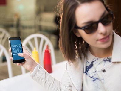 iPhone Being Held By Woman With Sunglasses At A Diner Restaurant Mockup