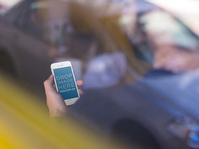 White iPhone SE Being Held By A Man Near A Car Reflection Mockup a13999