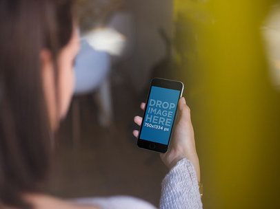 Over-the-Shoulder Mockup of a Woman Using an iPhone 6 in Portrait Position