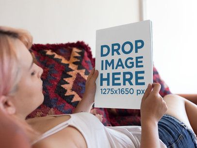 Mockup of a Young Girl With Pink Hair Looking at a Magazine While Lying Down in her Sofa a14368