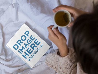 Mockup From Above of a Woman Reading a Book and Drinking a Tea While in Bed