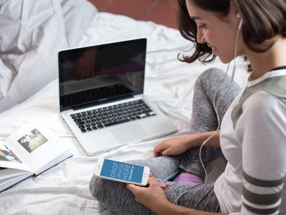 Short Haired Girl Using Her White iPhone 6 While Sitting on Her Bed a14258