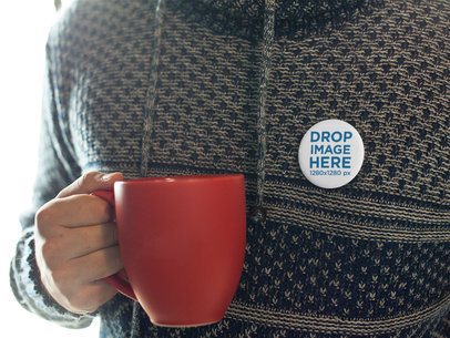 Mockup of a Button on a Man Sweater While Having a Coffee in a Red Mug