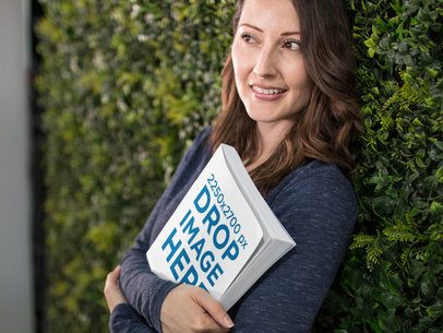 Pretty Woman Happily Holding a Book While Lying Against a Wall Covered With Plants Template a14431