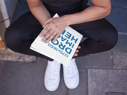 Template of a Young Man About to Read a Magazine While Sitting on the Street