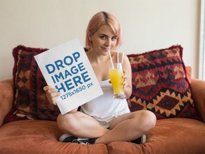 Smiling Girl With Pink Hair Drinking an Orange Juice and Holding a Magazine While Sitting in a Sofa Template a14366