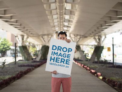 Hipster Dude Holding a Big Poster While Below a Beautiful White Bridge Mockup