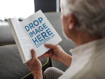 Mockup of an Old Man Reading a Book While Sitting Down on a Comfortable Sofa