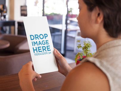 Young Girl Holding a Menu While at a Restaurant Mockup a14640