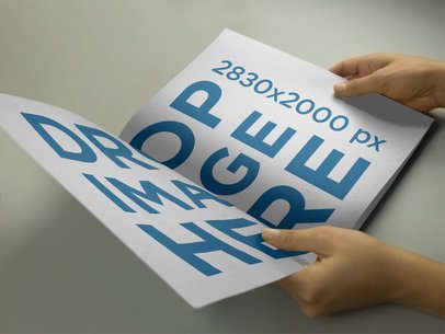Mockup of a Catalog Held by a Woman on a Gray Surface While Looking at It