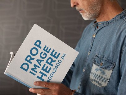 Elder Man Reading a Square Book While Near a Gray Wall Mockup