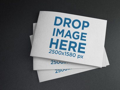 Mockup of Three Small Catalogs Stacked on a Black Surface