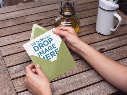 Template of a Green Invitation Envelope Being Opened by a Woman While on a Wooden Table
