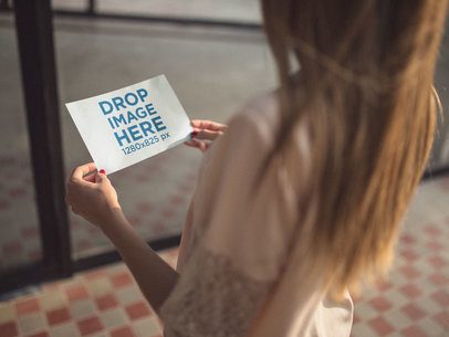 Over Shoulder Template of a Woman Holding a Horizontal Flyer Inside a Room