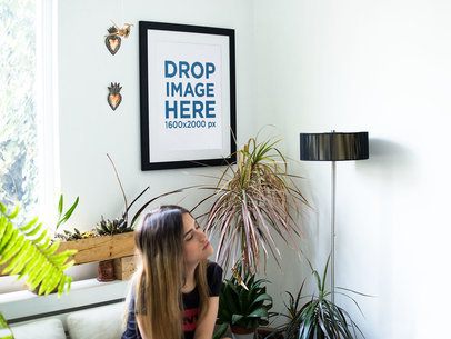 Young White Woman Sitting Down Inside a Waiting Room While a Framed Art Print Template is on the Wall