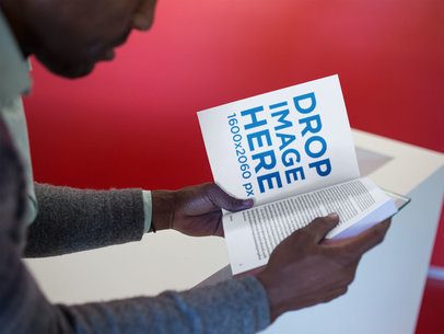 Man Reading a Book Mockup While Sitting Down in a Red Room