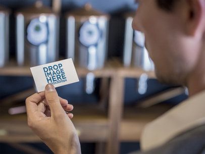 Young Man Holding a Business Card Mockup Inside a Store