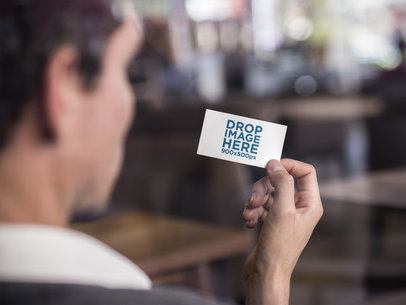 Man Holding a Business Card Mockup Indoors