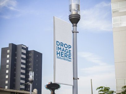 Mockup of a Vertical Banner Hanging from a Light Pole in the City